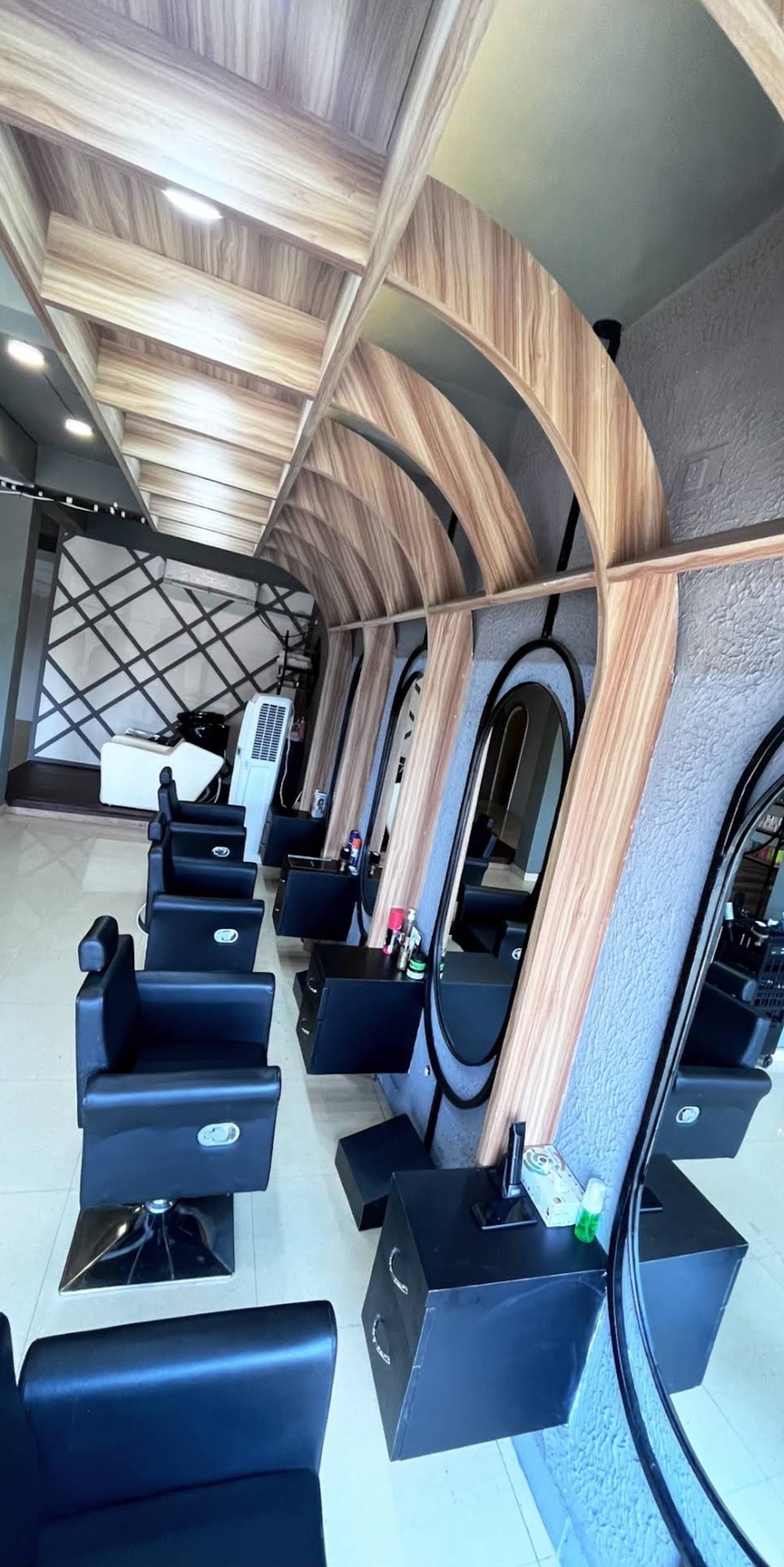 Row of black styling chairs under arched wooden ribs and oval mirrors